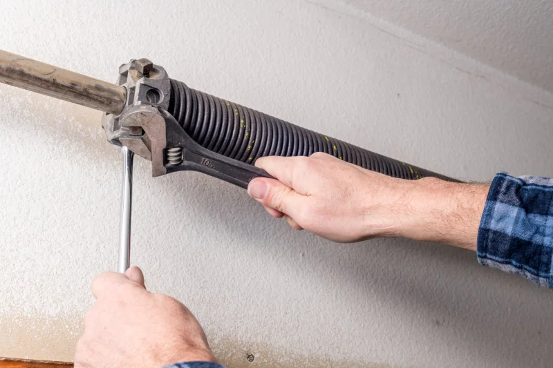 Technician adjusting a garage door torsion spring
